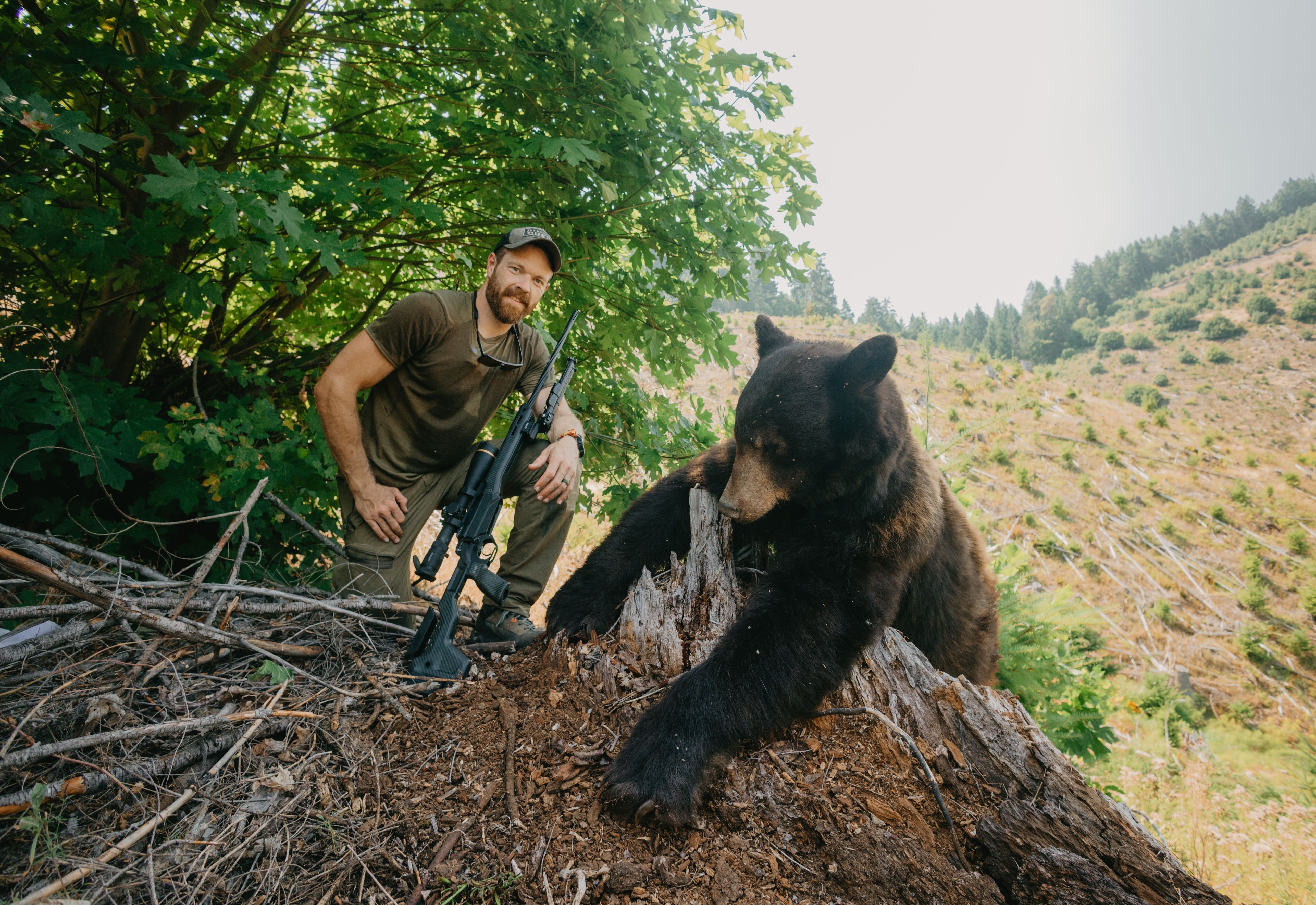 Hunter posing with a black bear in spring terrain